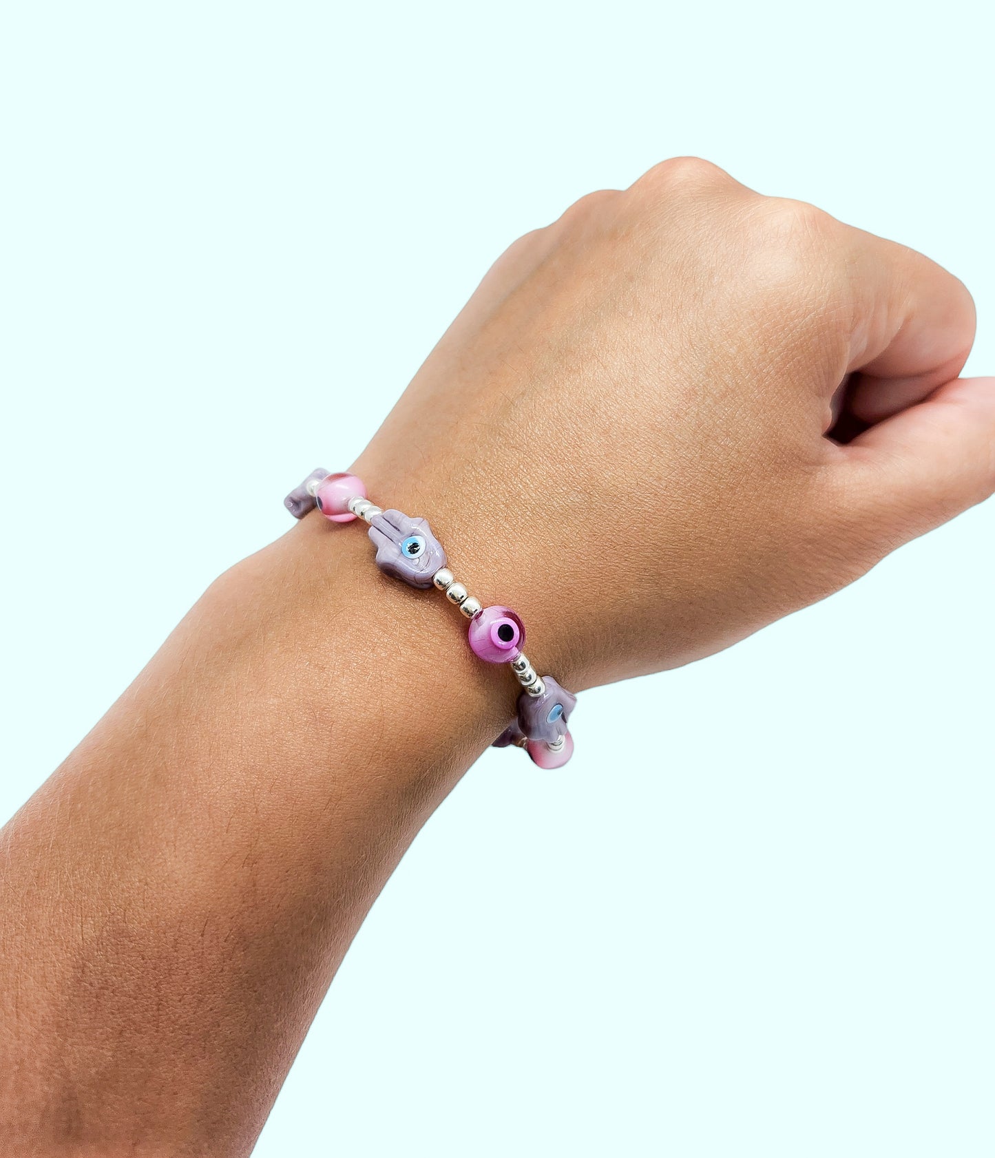 Pulsera de bolitas de plata con ojito turco rosa y mano morada
