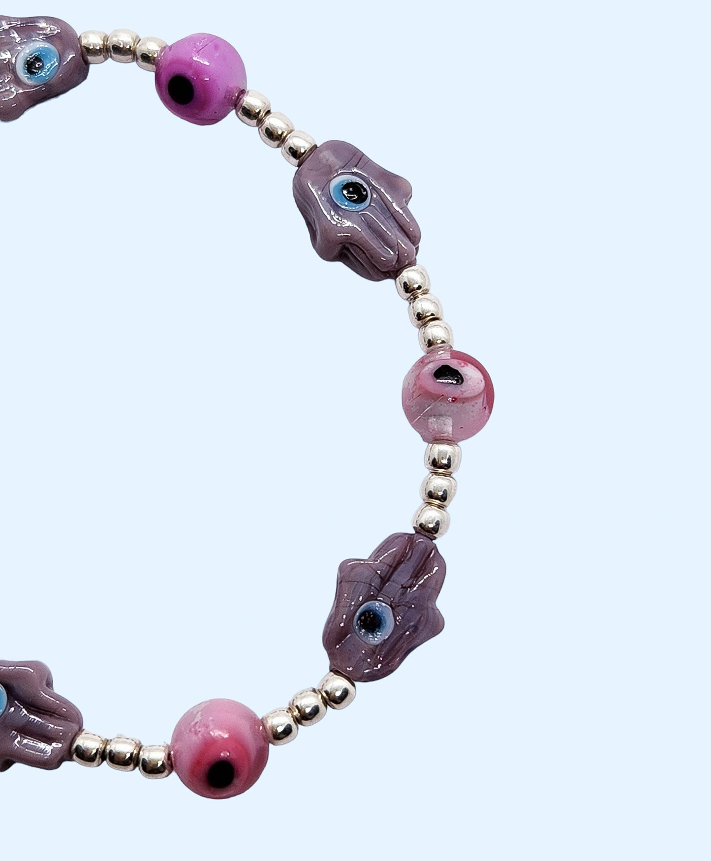 Pulsera de bolitas de plata con ojito turco rosa y mano morada