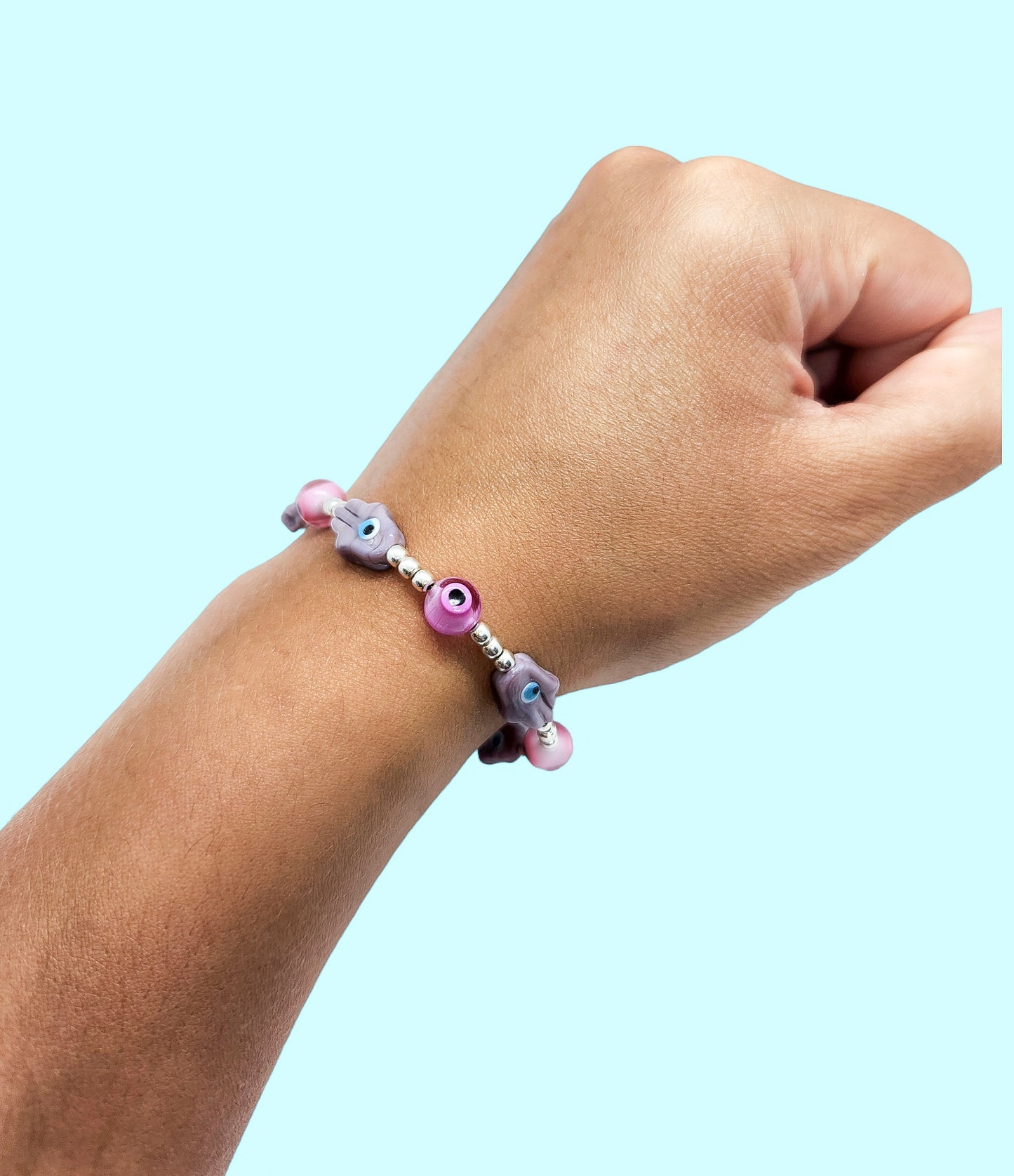 Pulsera de bolitas de plata con ojito turco rosa y mano morada